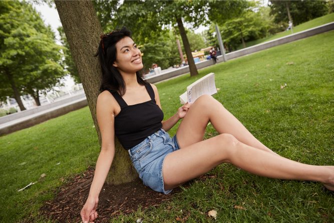 Woman reading a book next to a tree