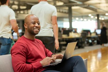 Man using laptop while talking to colleagues